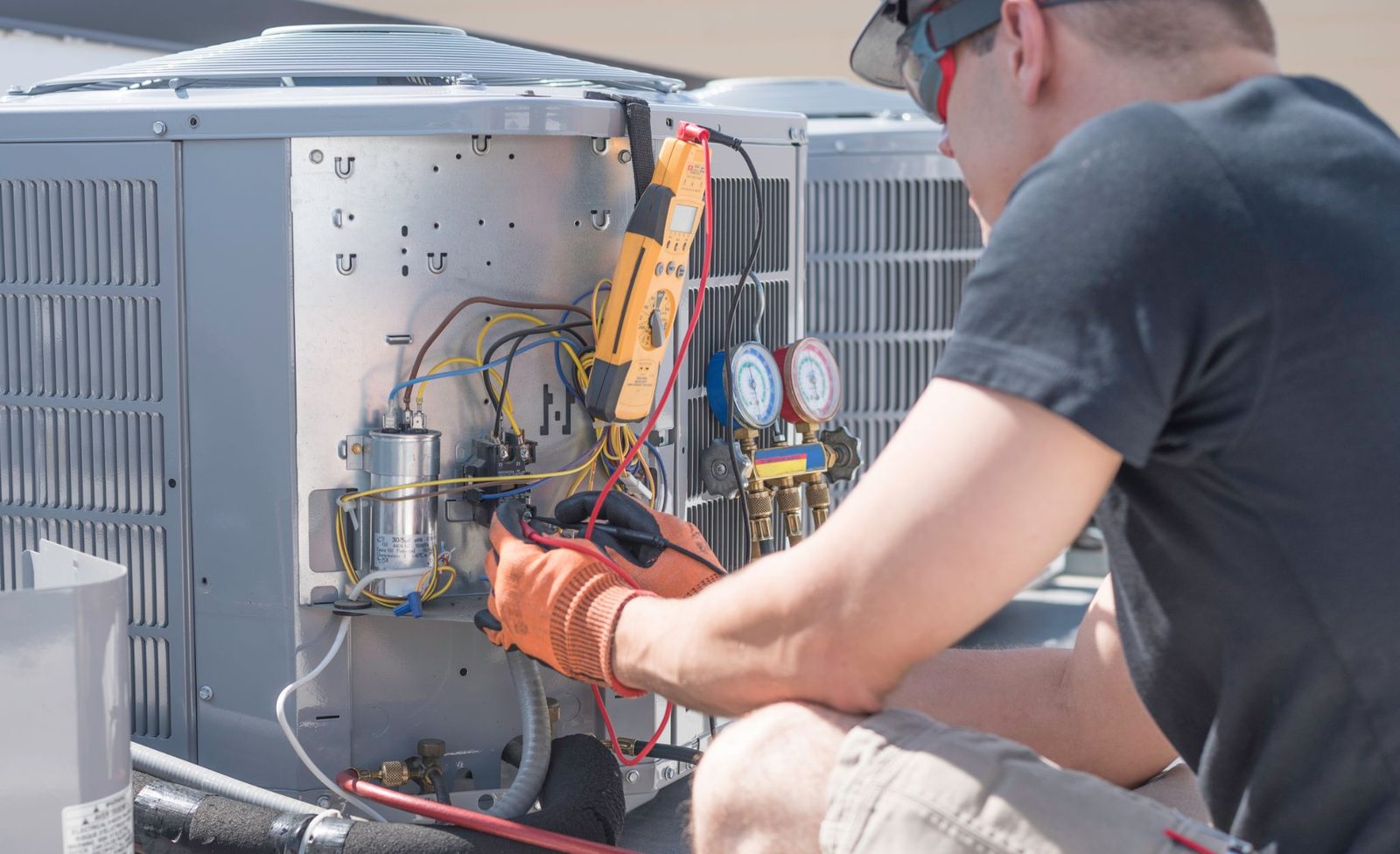 Technician connecting refrigerant gauges to an air conditioning unit